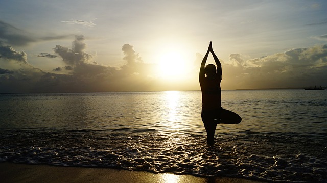 Persona realizando una postura de equilibrio en la playa al atardecer